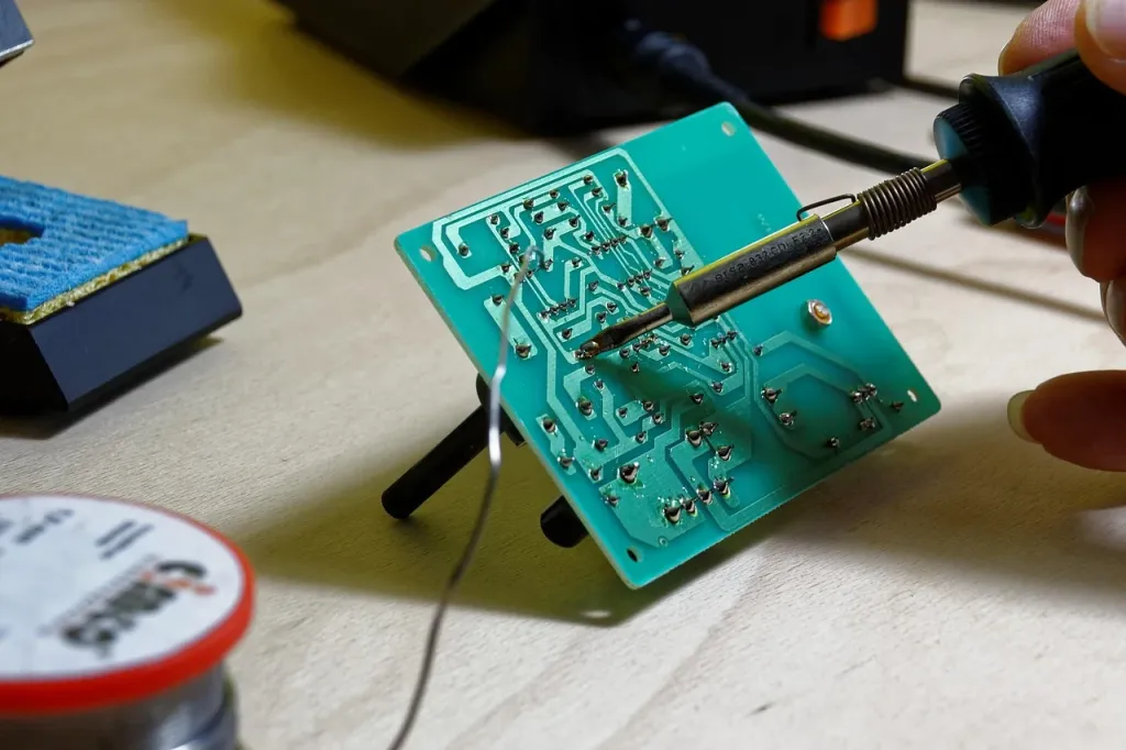 Zbliżenie na płytkę drukowaną z widocznym tranzystorem MOSFET podczas prac serwisowych przy elektronice.