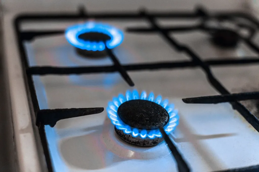 Zbliżenie na mosiężny zawór instalacji LPG z manometrem w komorze silnika samochodu, ukazujące detale złączy i uszczelek.